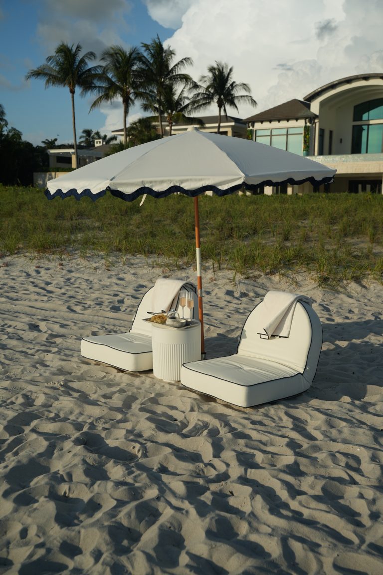 A styled bachelorette beach setup with fringe umbrellas